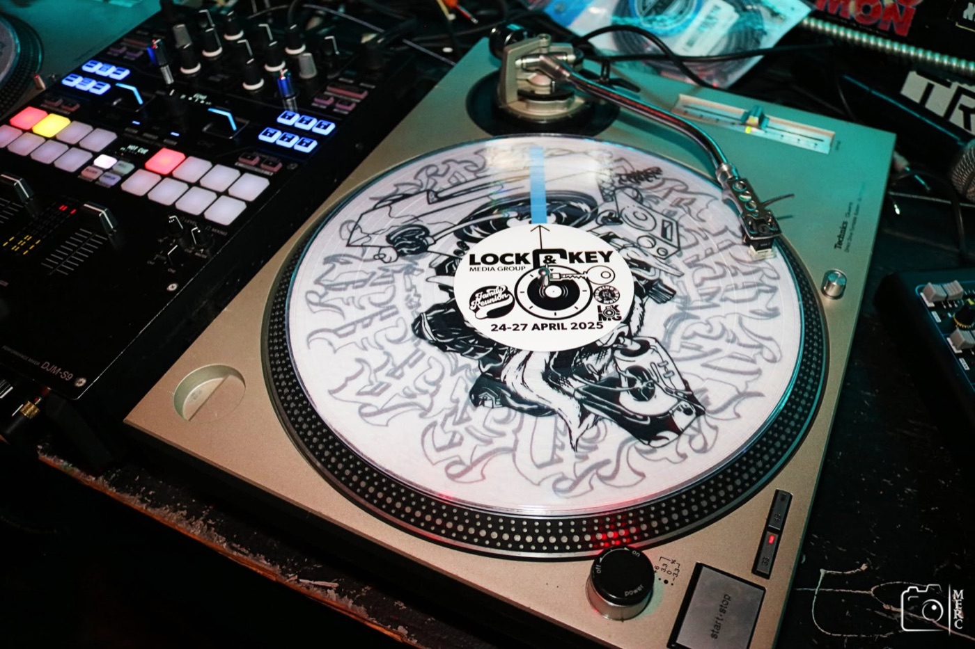 A picture disc spinning on DJ Dug Boogie’s Technics SL-1200 turntable beside his mixer